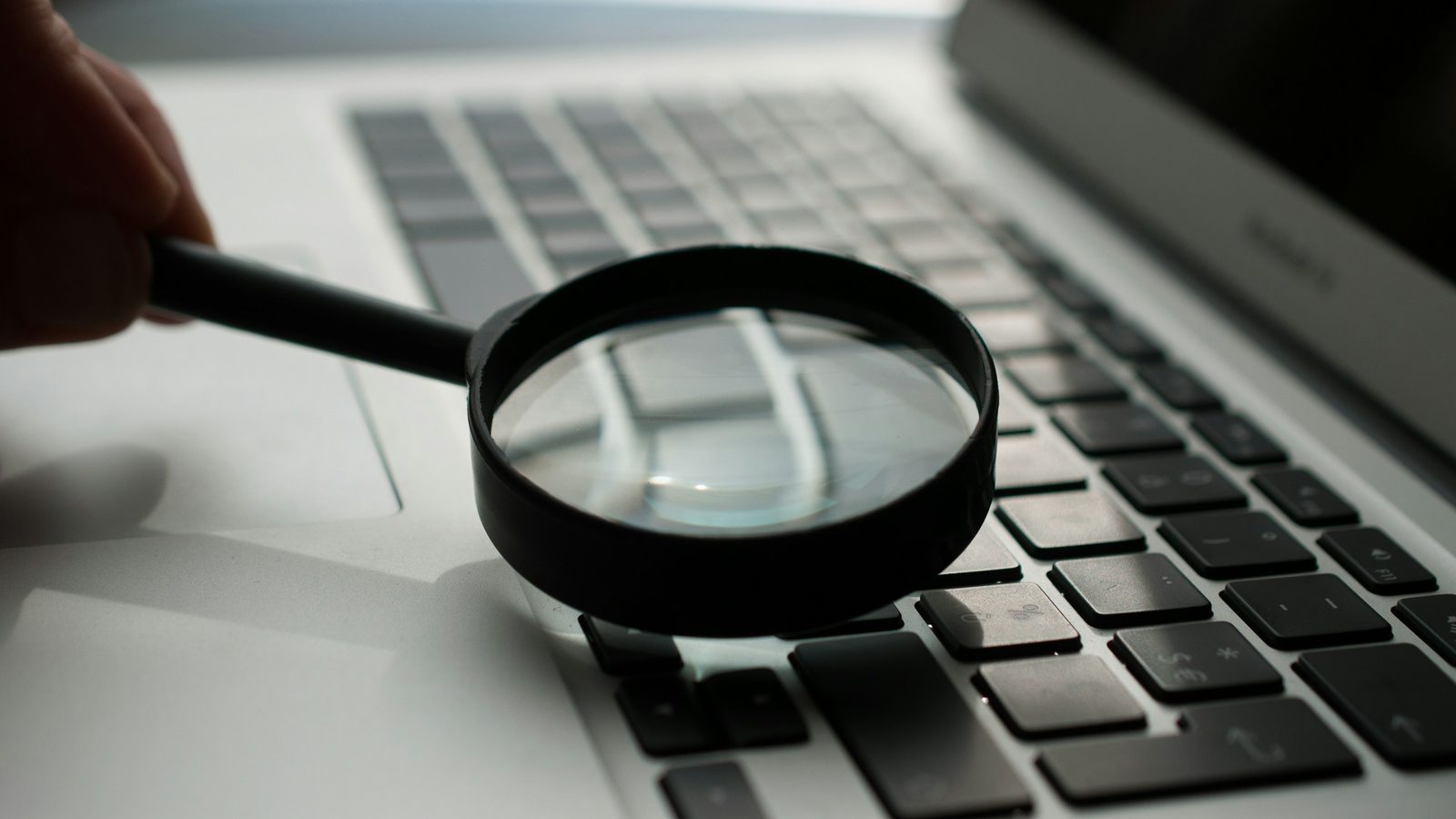 Lupe über der Laptop-Tastatur für einen genauen Online Casino Vergleich