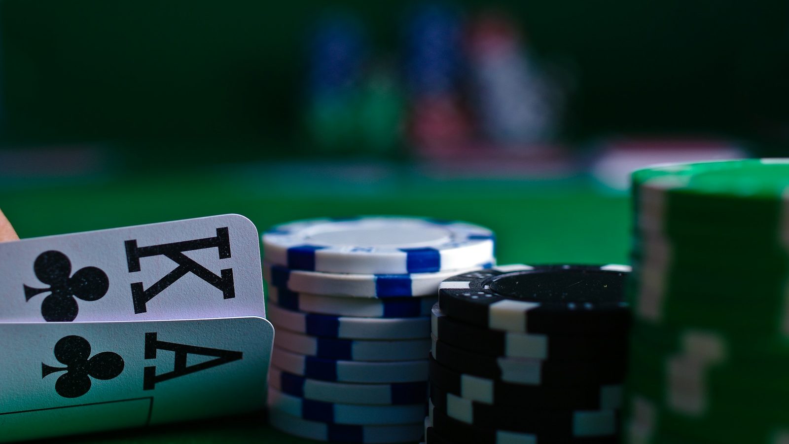 Hohe Chipstapel und Spielkarten auf grünem Filz, das Bild hinter dem Online Casino ohne Limit